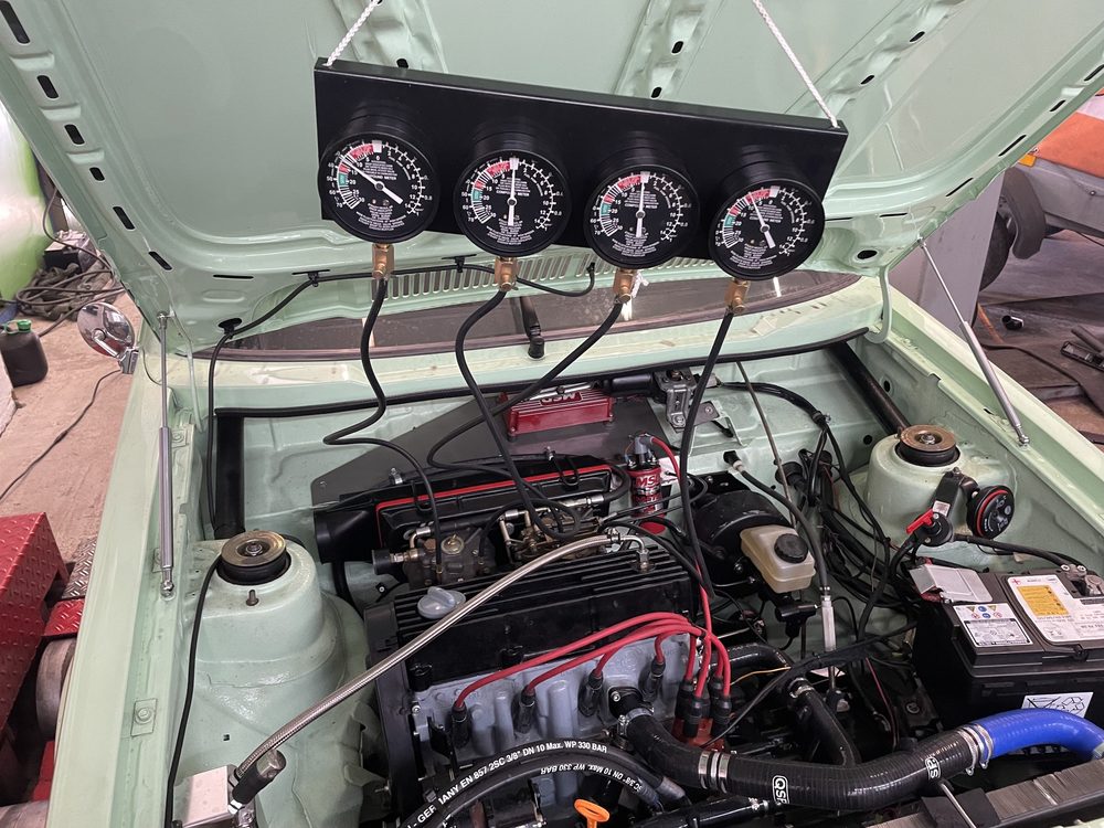Vier Unterdruckmessuhren an der geöffneten Motorhaube eines Klassikers, angeschlossen zum Synchronisieren der Vergaser